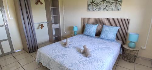 a bedroom with a bed with two stuffed animals on it at Fleur de Canne in Saint-Pierre