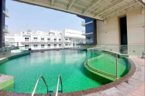 a large pool of green water in a building at New Large 2BR Apt Sleeps 10 Adults with Pool Gym Parking and Wifi in Dubai
