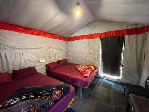 a room with two beds and a couch in a tent at Kaafirana Adventure Camps and Cottages in Shivpuri