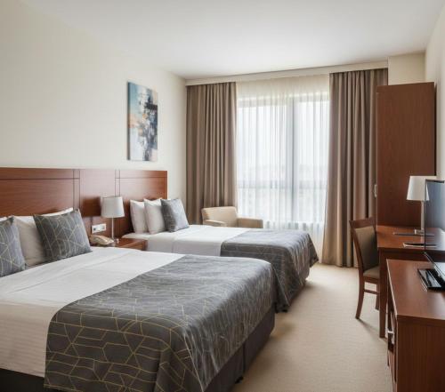 una camera d'albergo con due letti e una scrivania di Sabah Apart a Konya