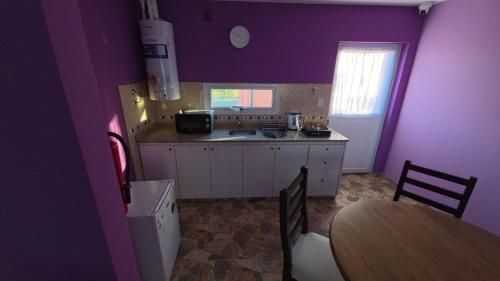 a kitchen with purple walls and a table and a sink at 7 Rayos y el Sol in Río Gallegos