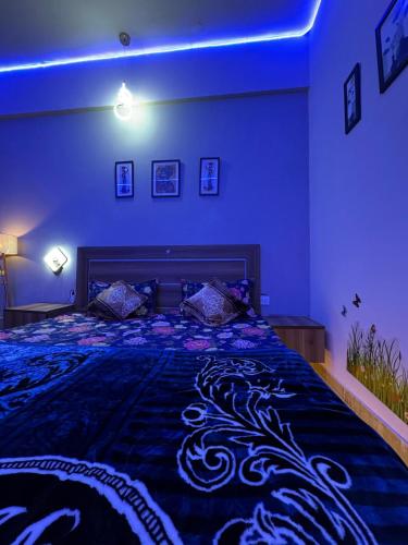 a bedroom with a large bed with blue lighting at Crown Suites in Greater Noida