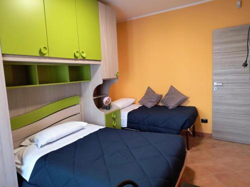 two beds in a small room with green cabinets at Il NIDO sul TICINO in Oleggio
