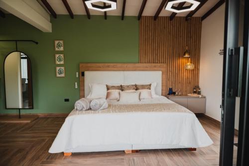 1 dormitorio con 1 cama blanca grande en una pared verde en Antara Resort, en Alcalá