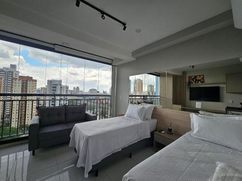 a bedroom with a bed and a couch and a large window at Apartamento com Piscina no Rooftop in São Paulo
