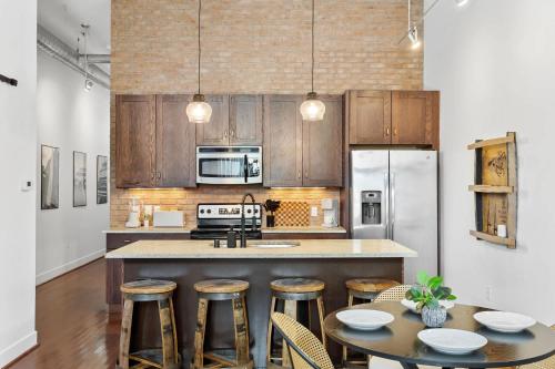 Una cocina con gabinetes de madera y una isla con taburetes de bar. en Urban Bourbon Escape - Downtown Louisville Getaway, en Louisville