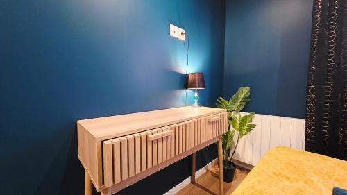 een kamer met een blauwe muur en een tafel met een lamp bij Suite Indigo - Centre Ville in Duinkerke