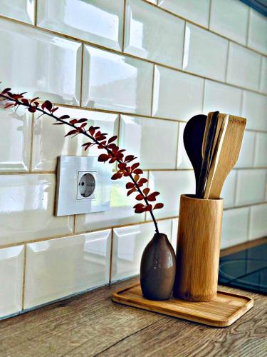 a counter with a vase and utensils on a cutting board at VerdeViu Apartments 1 Prima Residence Universitatii in Oradea