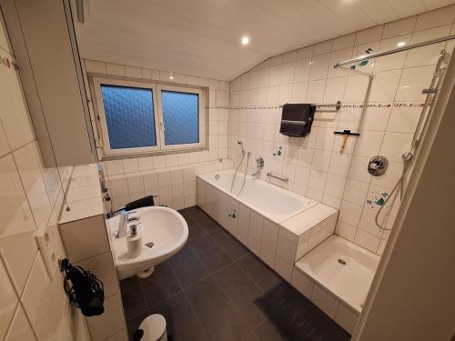 a bathroom with a sink and a tub and a toilet at Helle, großzügige Dachgeschosswohnung in Aichtal 