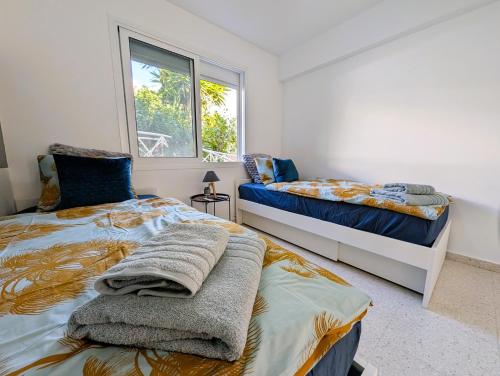 a bedroom with two beds and a window at Coral Bay Star - Direct sea location in Peyia