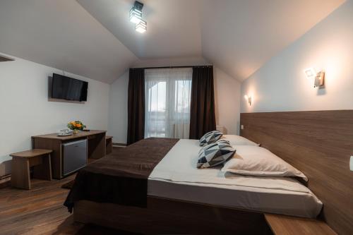 a bedroom with a large bed and a television at Pensiunea Casa Alexandra in Vatra Dornei