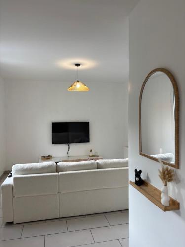 a living room with a white couch and a mirror at chambre sur le circuit des 24h du Mans in Ruaudin