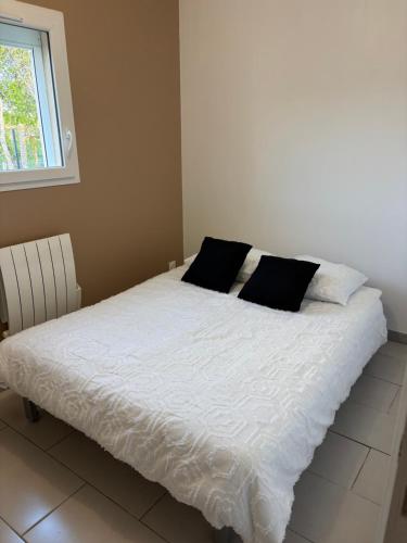 a bed with white sheets and black pillows on it at chambre sur le circuit des 24h du Mans in Ruaudin