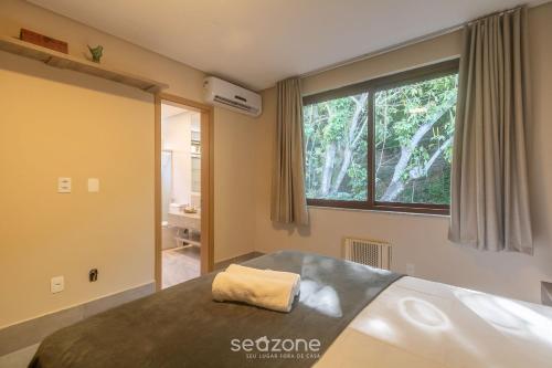 a bedroom with a bed and a large window at Aptos equipados em condomínio à beira-mar com área de lazer e piscina – VVAs in Arraial d'Ajuda