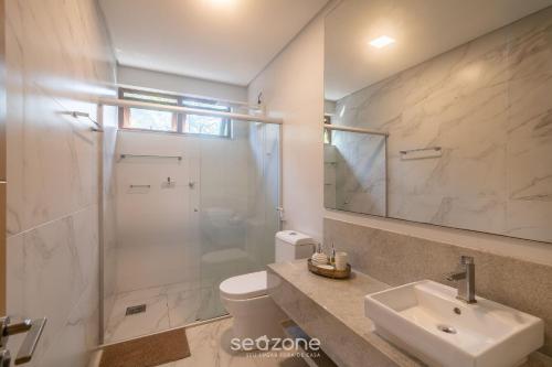 a bathroom with a toilet and a sink and a shower at Aptos equipados em condomínio à beira-mar com área de lazer e piscina – VVAs in Arraial d'Ajuda