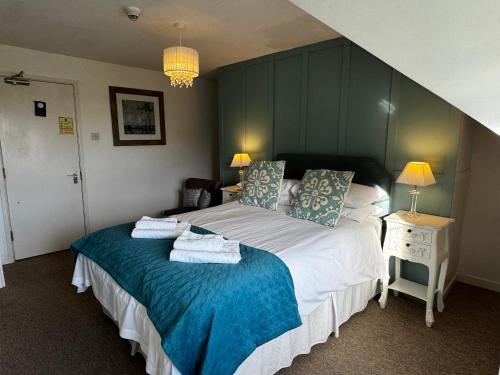 a bedroom with a large bed with towels on it at The Balnoon Inn B&B in St Ives