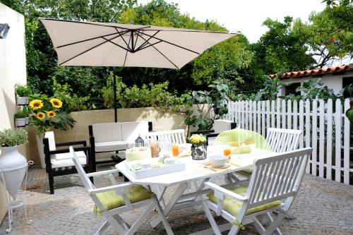 a white table and chairs with an umbrella at Casa da Ribeira in Aveiro