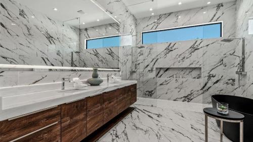 Sleeps 25 2 Luxury Villas w Pool Spa Putting Green Bravo by AvantStay في إنديو: حمام مع حوض وجدار من الرخام