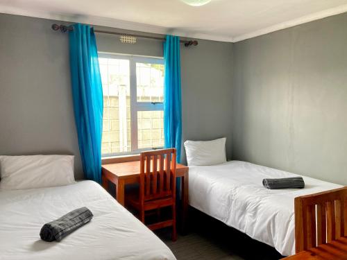 Unit 2 TraversHub Sleeps 6 Self-Catering Group Belhar, CT في Belhar: غرفة بها سريرين وطاولة ونافذة