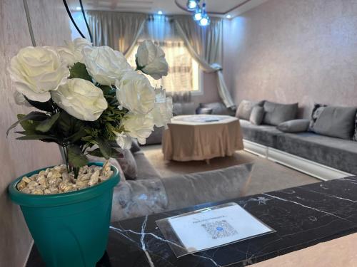 una sala de estar con un jarrón con flores blancas sobre una mesa en appartement luxe, en Berkane