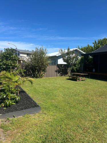 a yard with a picnic table and a bench at Coastal Escape - Cooks Beach in Cooks Beach