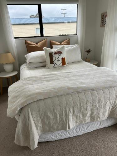 a bedroom with a white bed with a large window at Coastal Escape - Cooks Beach in Cooks Beach