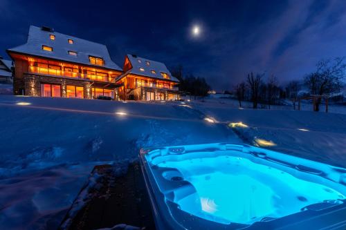 a hot tub in the snow in front of a house at Janiołów Wierch 43 Jacuzzi i Sauna in Groń