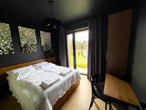 een slaapkamer met een bed, een tafel en een raam bij Dom w czerni in Górniki