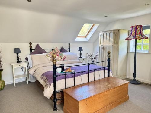 ein Schlafzimmer mit einem Bett mit lila Laken und einer Holzbank in der Unterkunft Charming Dog-Friendly Guesthouse in Sidbury