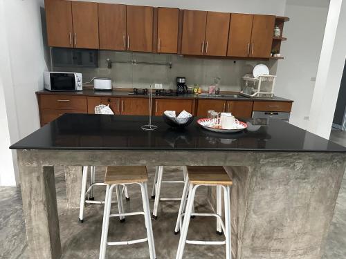 Una cocina con una encimera negra y dos taburetes de bar. en Samui Zenity, en Mae Nam