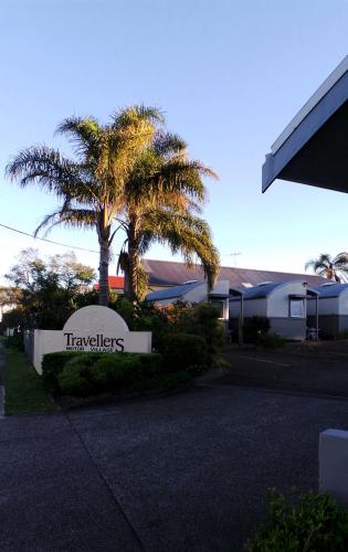 a sign in front of a building with a palm tree at Travellers Motor Village in Newcastle