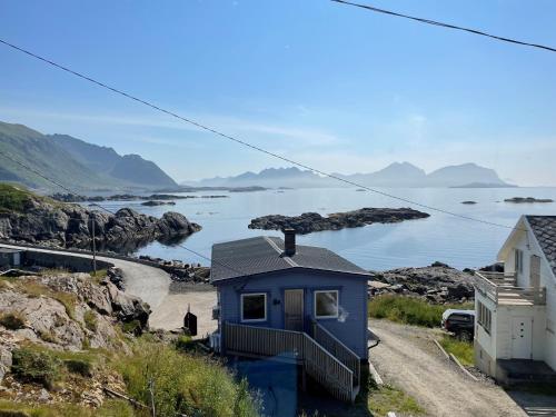 een blauw huis op een heuvel met uitzicht op het water bij Arctic Nest in Nyksund