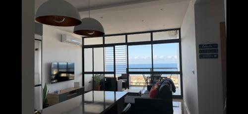 een woonkamer met een tafel en uitzicht op de oceaan bij Ponta do Sol "A Boa Vida" in Ponta do Sol