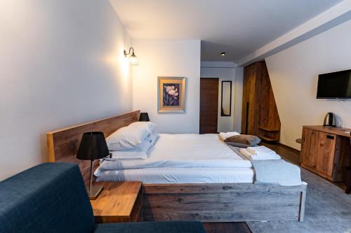 a bedroom with two beds and a tv and a couch at Maar Hotel Brezovice in Prevallë