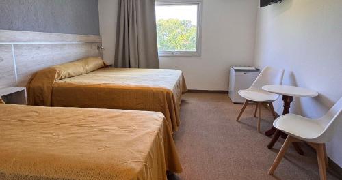 a hotel room with two beds and a table and chairs at Encanto Del Mar in Ostende