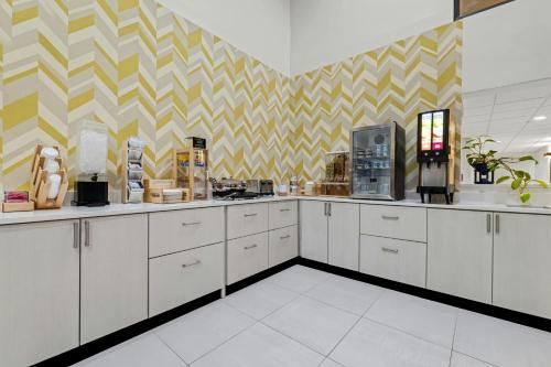 a kitchen with white cabinets and a yellow and white wallpaper at City Express by Marriott Yulee in Yulee