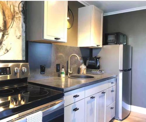 a kitchen with white cabinets and a sink and a refrigerator at Village District Condo in Raleigh