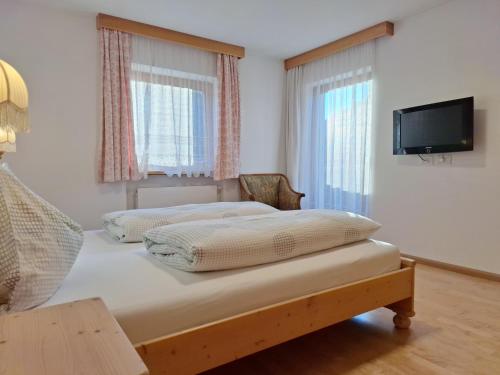 a bedroom with two beds and a flat screen tv at Apartments Insam in Santa Cristina in Val Gardena