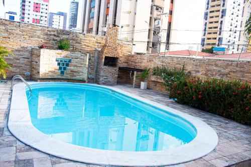 a swimming pool in front of a brick wall at Pousada Aconchego Manaíra in João Pessoa