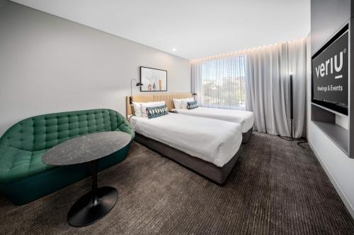 a hotel room with two beds and a green couch at Veriu Green Square in Sydney