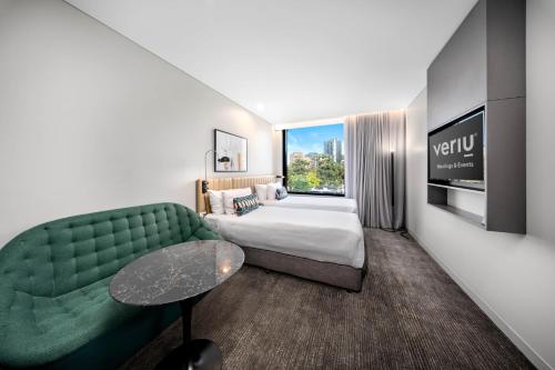 a hotel room with a bed and a green couch at Veriu Green Square in Sydney
