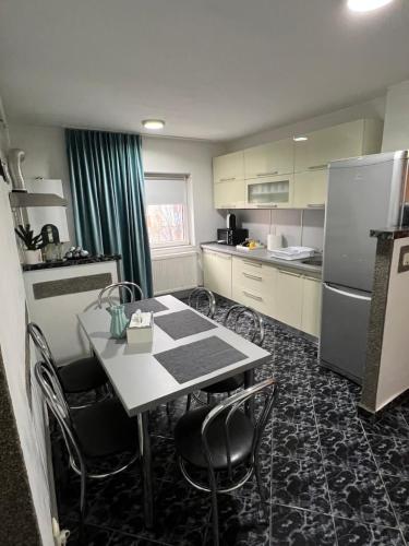 a kitchen with a table and chairs and a refrigerator at Apartament doua camere in Baia Mare