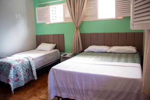 two beds in a room with green walls and windows at Pousada Aconchego Manaíra in João Pessoa