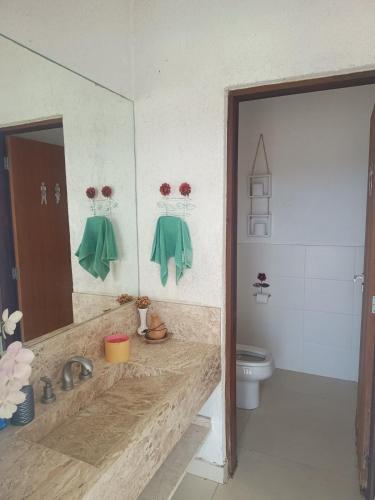 a bathroom with a sink and a mirror and a toilet at Casa de Alto Padrão Piscina e Linda Vista para o Mar in Caraguatatuba