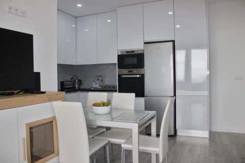 Una cocina con mesa y sillas y un refrigerador. en Apartamento Laranjeiras dois, en Bicas