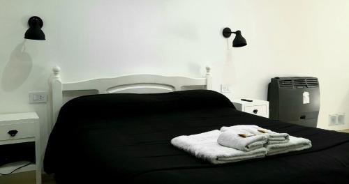 Disfruta Mucho !!! في إل كالافاتي: سرير أسود عليه منشفة بيضاء