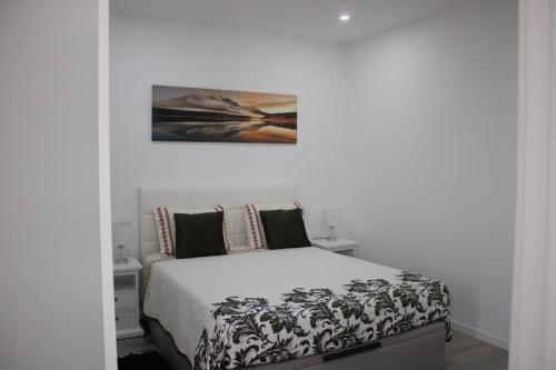 a bedroom with a bed and a painting on the wall at Apartamento Laranjeiras dois in Palhota