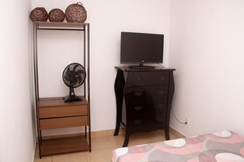 una camera da letto con televisore e comò con specchio di Casinha Vale do Sol a Nova Lima