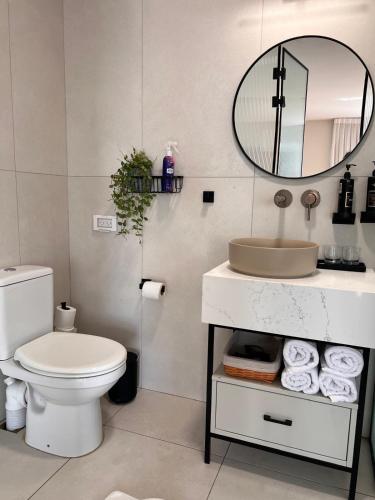 a bathroom with a toilet and a mirror and towels at Sun Circle - וילה יוקרתית עם בריכה מול הכנרת in Poriyya