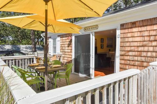 een patio met een tafel en een parasol op een veranda bij Cottage w Private Association Pool in Wellfleet